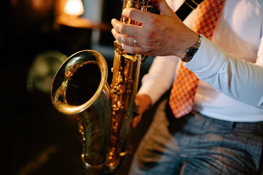 A man in a suit intricately playing a saxophone indoors, showcasing musical passion.